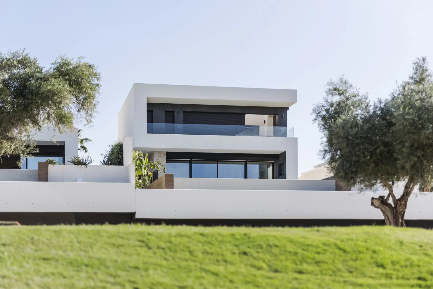 Photo of a finished two-storey villa in phase R-11, seen from the golf course lawn between olive trees